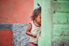 A little girl peeks around the corner in Copan, Honduras