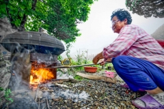 An anjuna (grandmother) stokes the flames in preparation for cooking a potato dinner in South Korea
