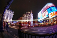 The streets of London are filled with bright signs and quickly-moving traffic