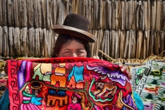 A Peruvian blanket vendor shows off her wares on the Uros floating islands in Lake Titicaca, Peru