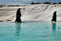 Women wear traditional burkas - even as they walk alongside the thermal springs of the Pamukkale Cascades in Turkey