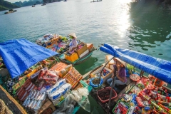 Snack vendors approach tourists by boat in Halong Bay