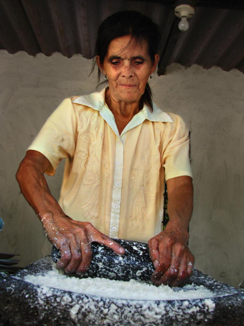 Dionora's mom rolls tortillas on a traditional stone block in El Salvador