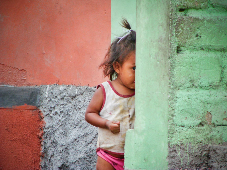 A little girl peeks around the corner in Copan, Honduras