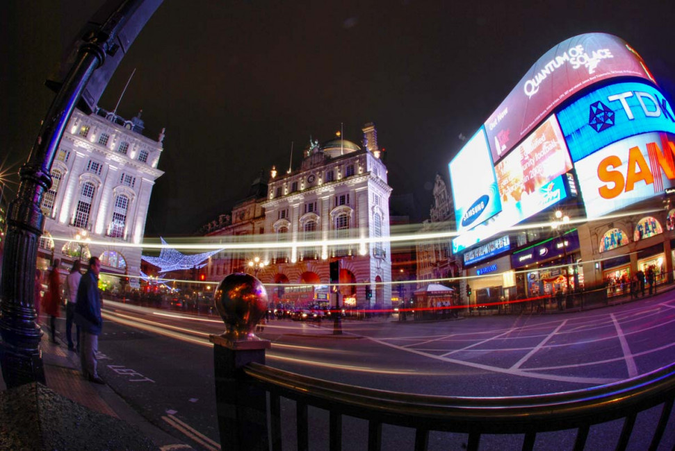 The streets of London are filled with bright signs and quickly-moving traffic