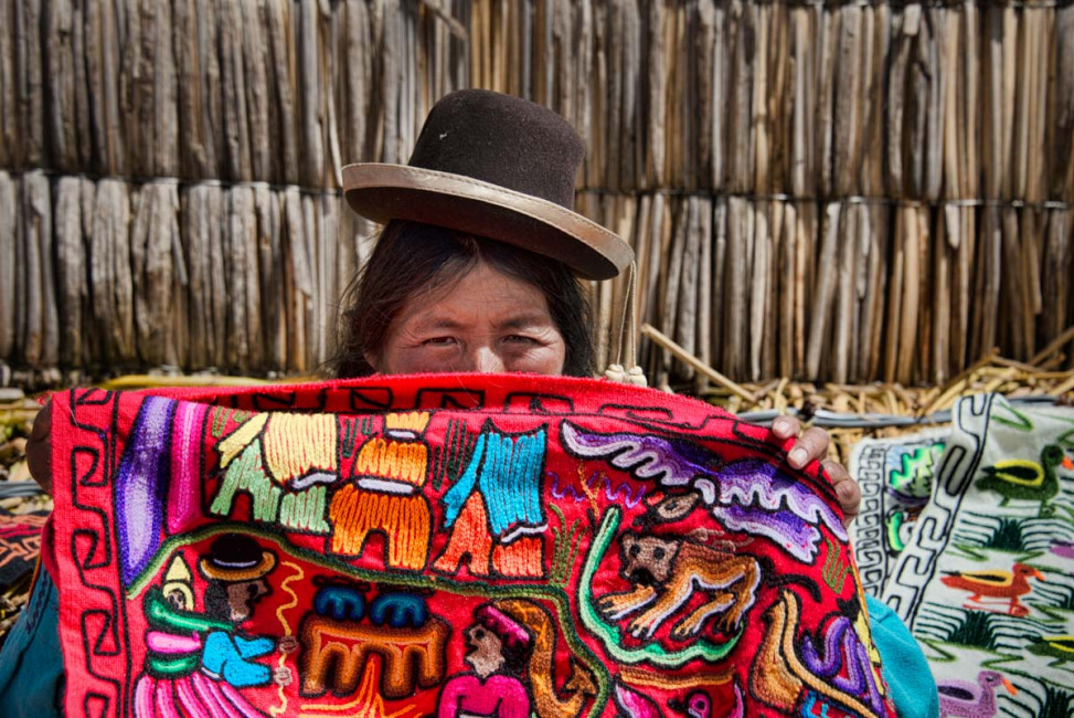 A Peruvian blanket vendor shows off her wares on the Uros floating islands in Lake Titicaca, Peru