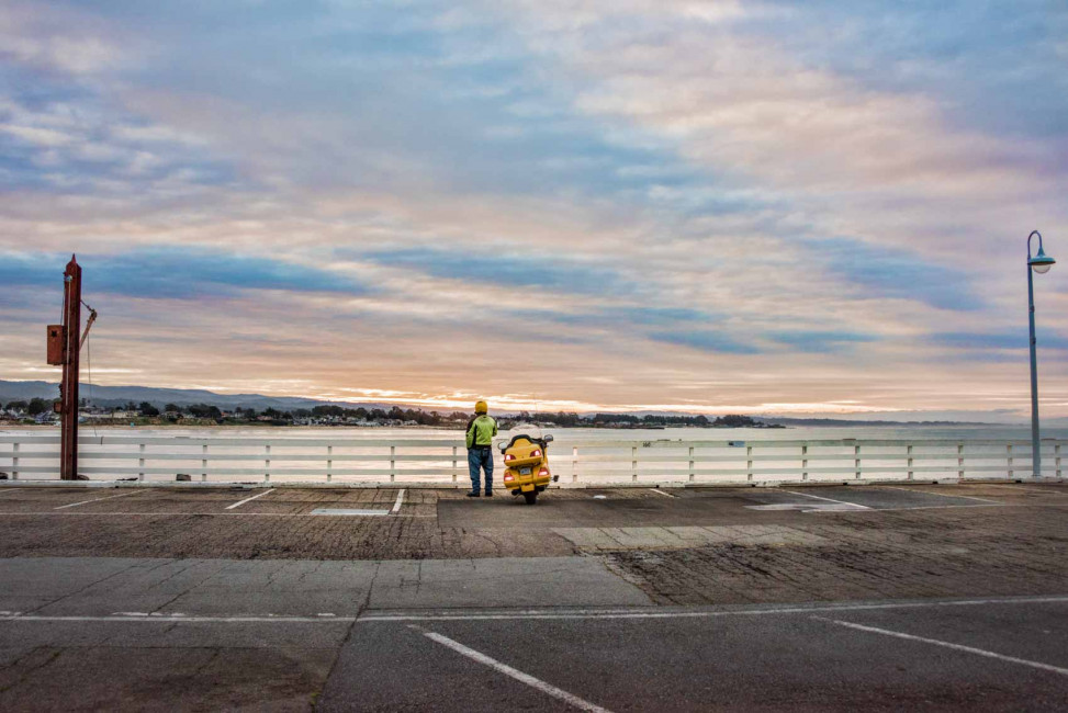 A motorcyclist takes a coffee break at sunrise on the Santa Cruz Wharf