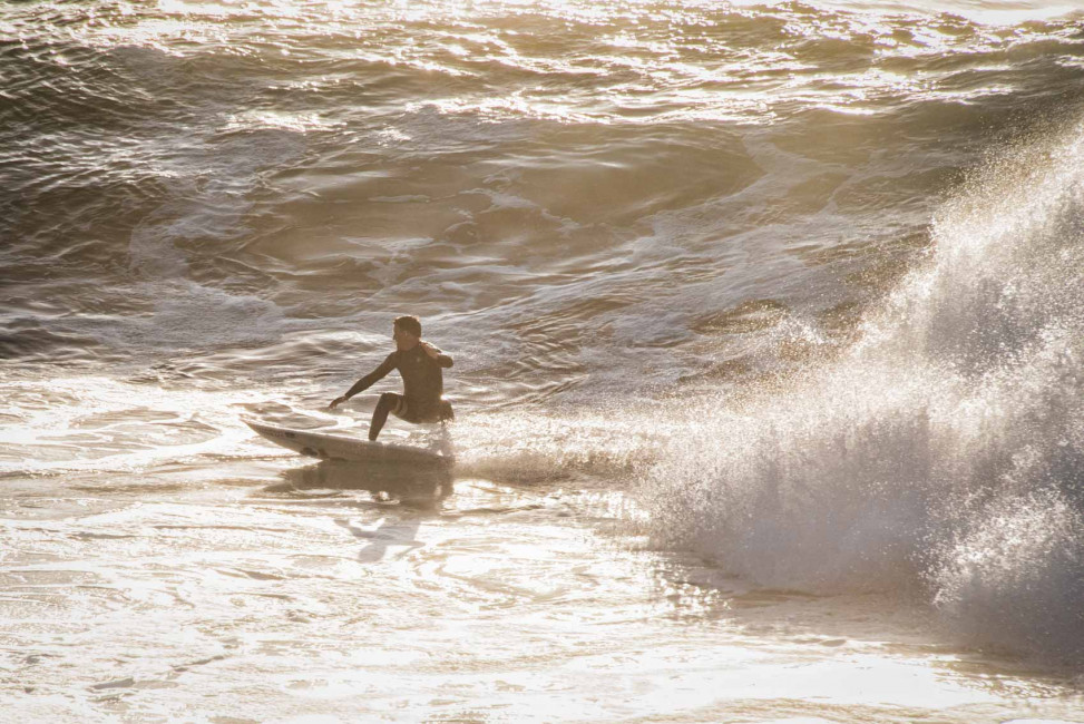 A surfer in the Pacific Ocean alongside Westcliff Drive in Santa Cruz, CA
