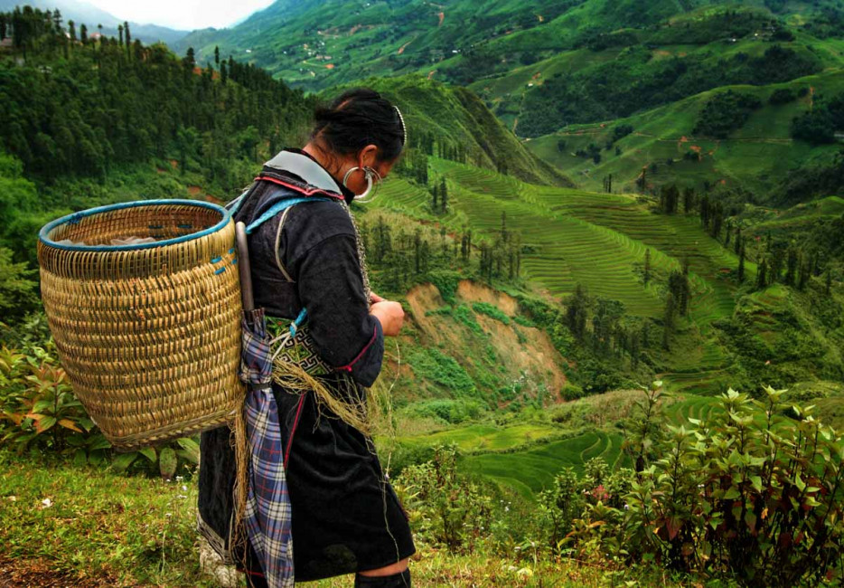 A Xao tribeswoman takes a break from hiking to weave a gift for a tourist