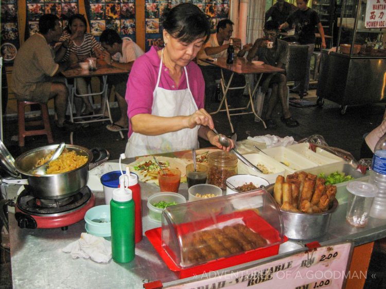 A local woman makes spring rolls on the streets of Melaka, Malaysia