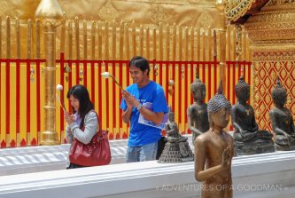 Locals walk around a temple while praying at Doi Suthep in Chiang Mai, Thailand