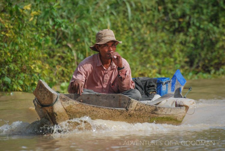 A local man enjoys a smoke while piloting down the river en-route to Kampong Phluk