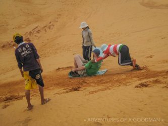 Locals push me down the red sand dunes of Mui Ne, VietNam