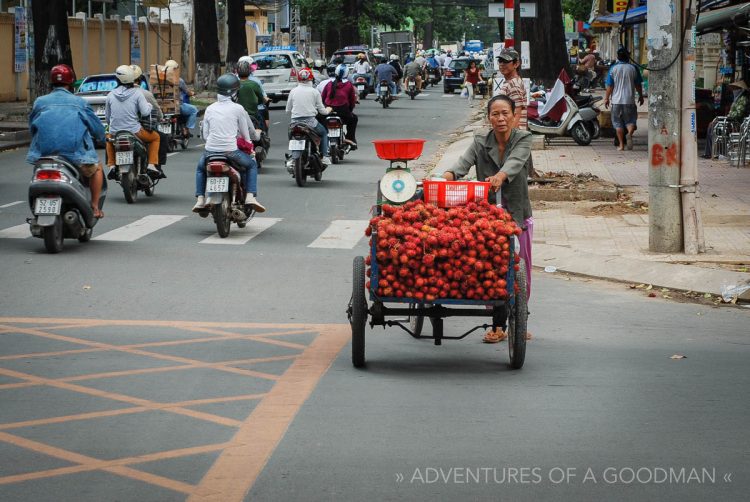 A street vendor pushes a cart of rambutan fruit down Ho Chi Min