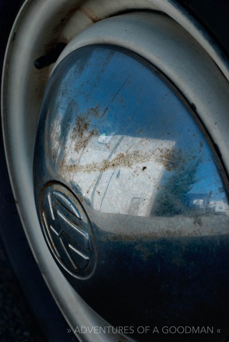 A building reflects in the hubcap of a classic hippie Volkswagen Bus