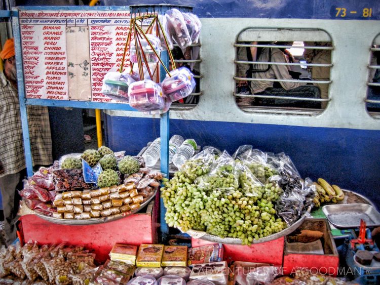A food vendor rolls his cart over to an Indian train window at a station