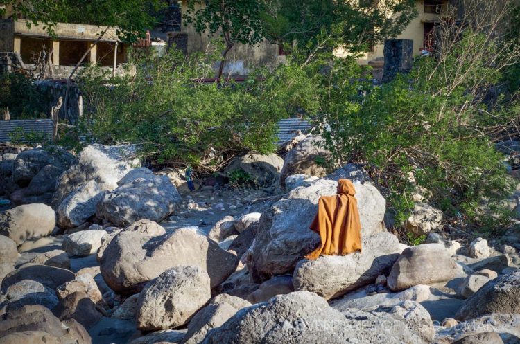 A local man meditates alongside the Ganges River in Rishikesh, India