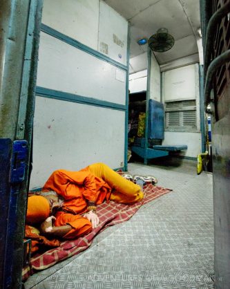 A Sadhu sleeping in the doorway of a Indian Overnight Train, stopped in the Haridwar train station