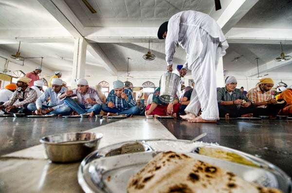 A man drops daal into the plates of hundreds of pilgrims at the Golden Temple Free Kitchen