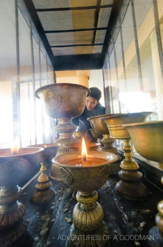 A devotee lights candles in oil vessels at Tsuglagkhang: the temple inside the Dalai Lama compound