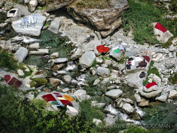 Monk robes dry along with Indian pants, shirts and other clothes by the Bhagsu waterfall in Dharamasala