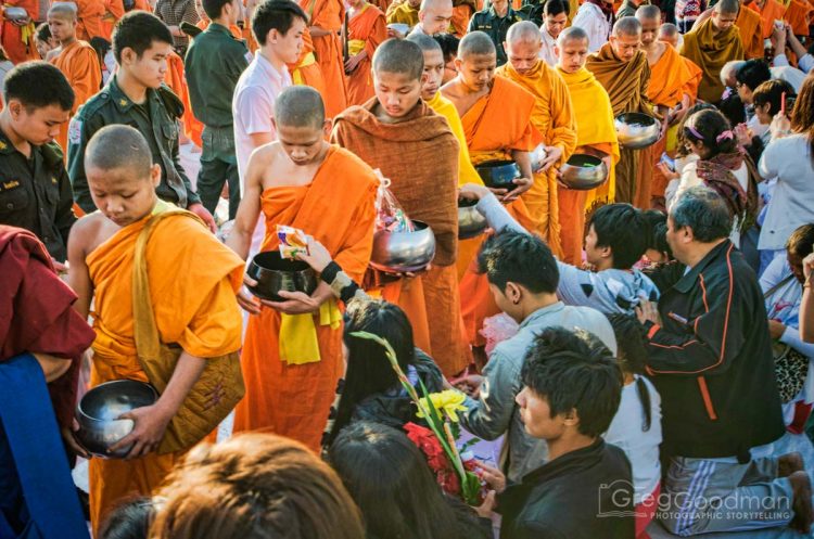 Devotees of all ages lined up to give alms to the monks