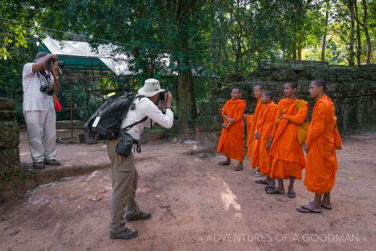Two tourists photograph a group of young monks in Ta Phrom, Angkor, Cambodia