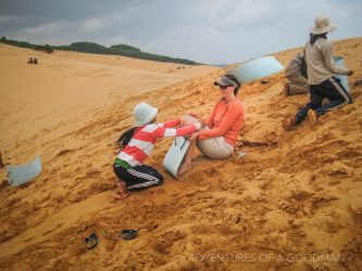 Carrie sleds down the red sand dunes of Mui Ne, VietNam
