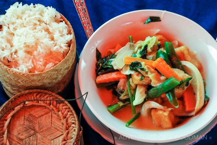 Tofu and veggies in a green coconut sauce with sticky rice in a basket