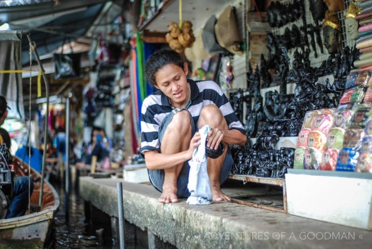 A woman dusts off her wares at the Damnoen Saduak Floating Market in Thailand