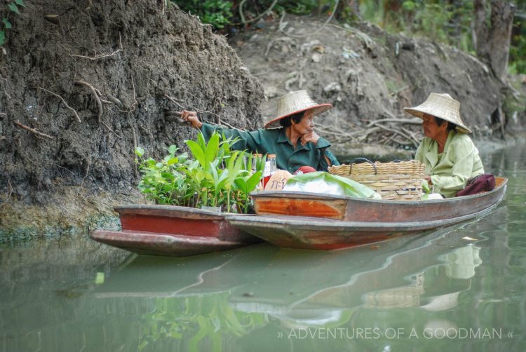 Two produce vendors stop for a chat at the Damnoen Saduak Floating Market in Thailand