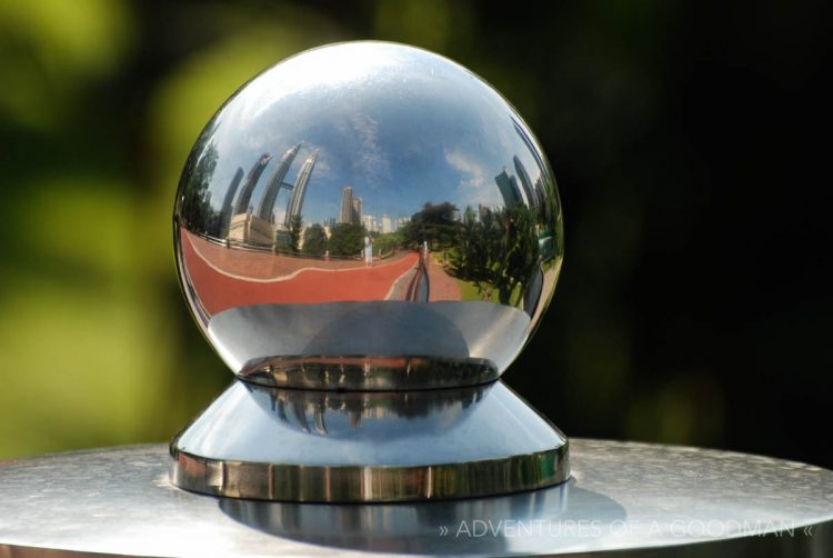 The Petronas Towers reflect in a metal globe in a park in Kuala Lumpur, Malaysia