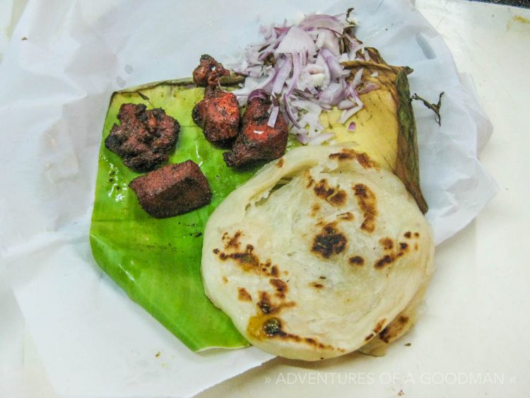 Tandoori chicken, parrota and onions, served on a banana leaf in India