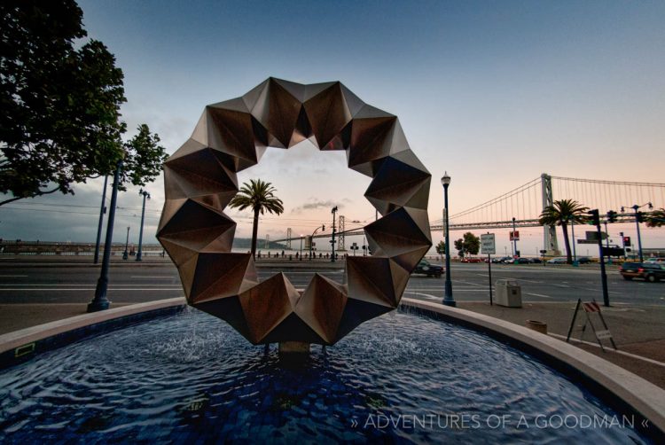 A sculpture on the Embarcadero with the Bay Bridge looming behind San Francisco