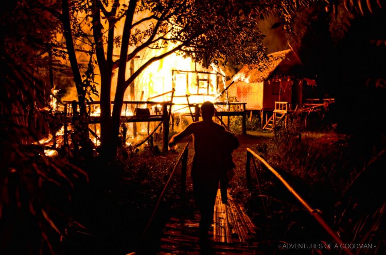 Christian escapes across a bamboo bridge after running into his burning bamboo hut to save his favorite sweatshirt