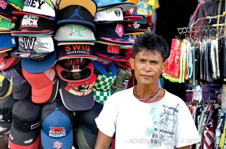 He kinda forgot to smile -- a baseball cap vendor at the Baclaran Market - Manila, Philippines