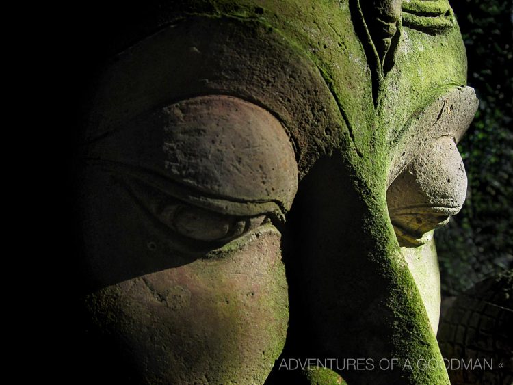 A mossy Buddha face at the Baan Phor Liang Meun's Terra-Cotta Arts garden in Chiang Mai, Thailand