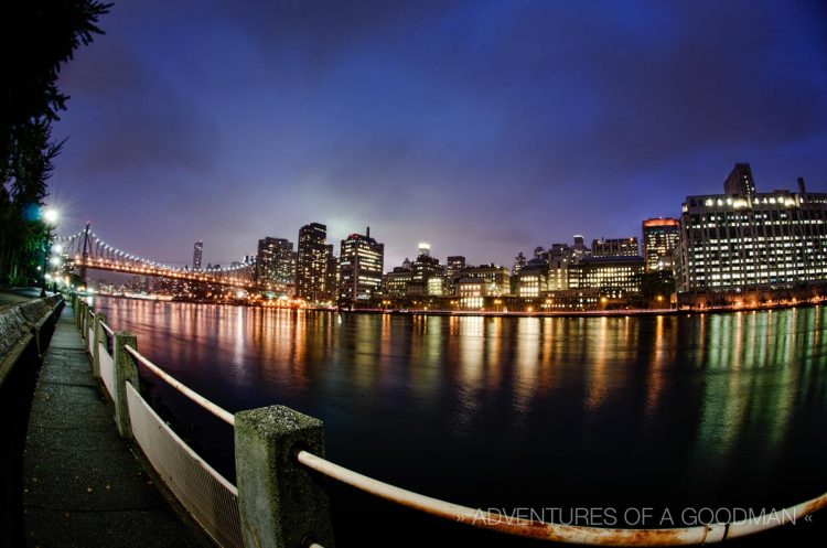 A rainy blue hour view of Manhattan and the Queensboro Bridge, as seen from Roosevelt Island in New York City