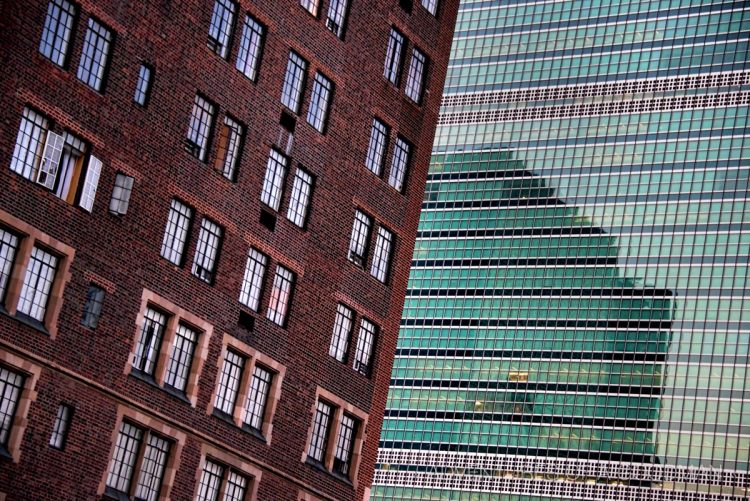 The windows of the United Nations are a stark contrast to the traditional brick apartment buildings next to it