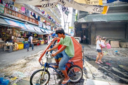 A pedicab splashes through the puddles of the Baclaran Market in Manila, Philippines