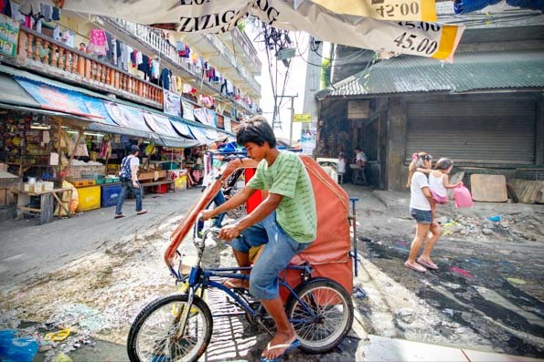 A pedicab splashes through the puddles of the Baclaran Market in Manila, Philippines