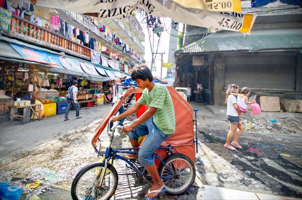 A pedicab splashes through the puddles of the Baclaran Market in Manila, Philippines