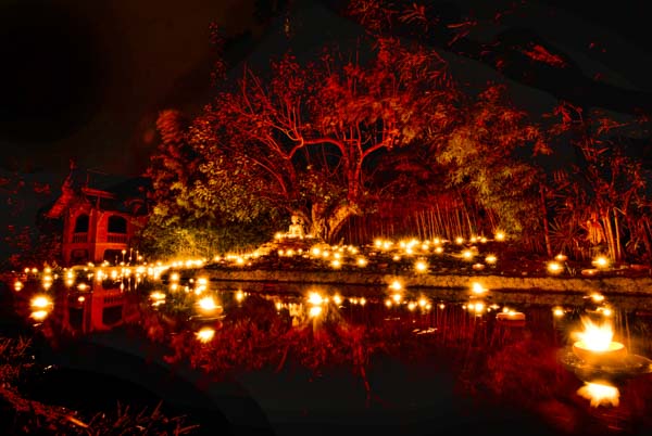 Candles and a Buddha statue reflect in the pond outside Wat Pan Tao in Chiang Mai