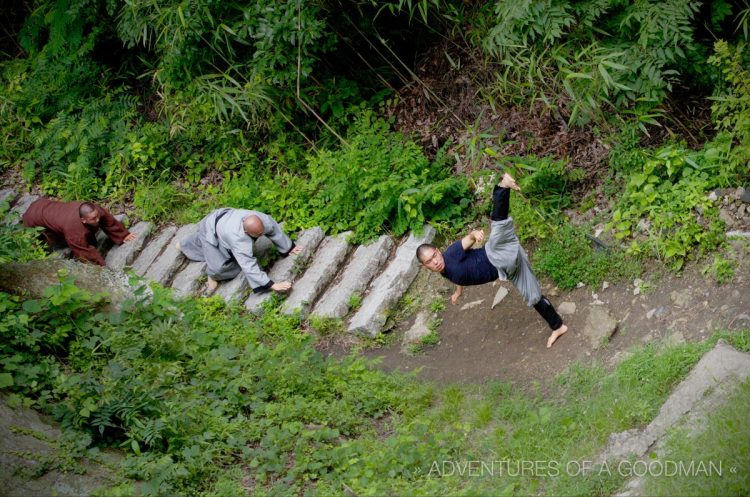 The monks do a series of pushups as they crawl down stairs. Once at the bottom, they perform a series of high leg kicks