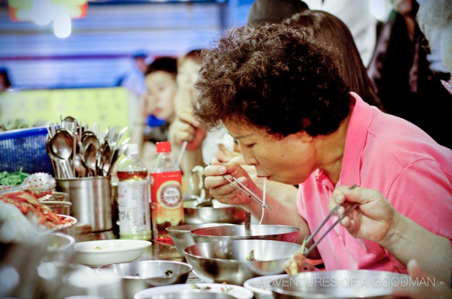 A local Korean woman enjoys a traditional bowl of noodle soup