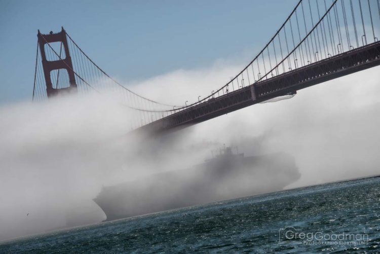 A cargo ship passes underneath a foggy Golden Gate Bridge in San Francisco, CA