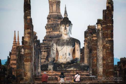 Early morning prayers in front of the giant Buddha statue at Wat Mahathat in Sukhothai