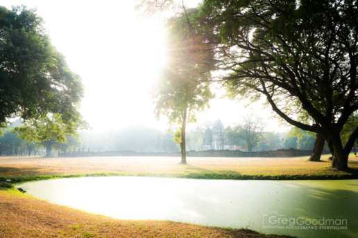 Sunrise over a pond with Wat Si Sawai in the distance
